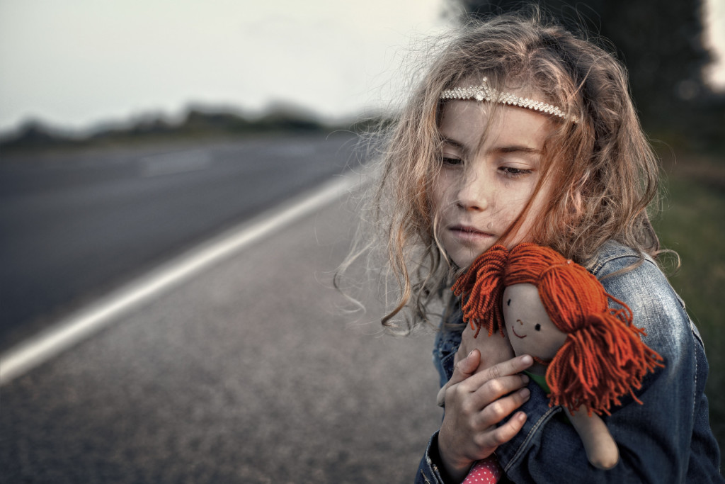 Desperate little girl orphan hugging a doll